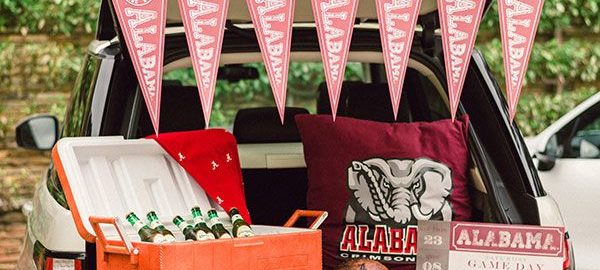 Trunk of a car filled with Alabama memorabilia and a cooler with beer.